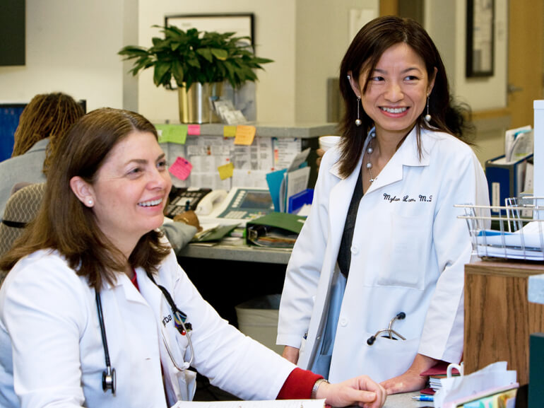 Two female doctors having a smiling and conversation at the nurses station.
