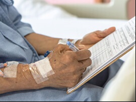 Close up of older patient's hands signing advanced directive paperwork.