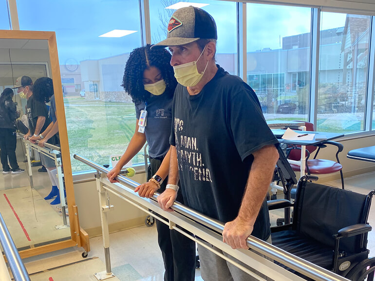Timmy Moltz working with his therapist on the parallel bars.