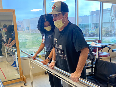 Timmy Moltz working with his therapist on the parallel bars.